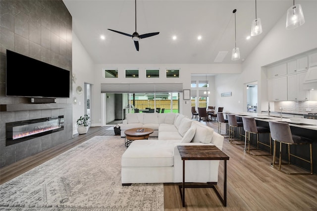 5350 Cherry Spring Dr, Spring, TX 77386 - living room featuring high vaulted ceiling, light wood-style flooring, a ceiling fan, a tile fireplace, and recessed lighting