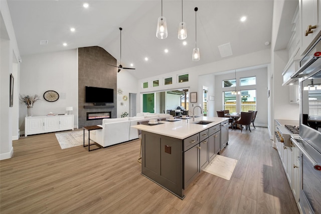 5350 Cherry Spring Dr, Spring, TX 77386 - kitchen with high vaulted ceiling, light countertops, a fireplace, light wood-style floors, and a center island with sink