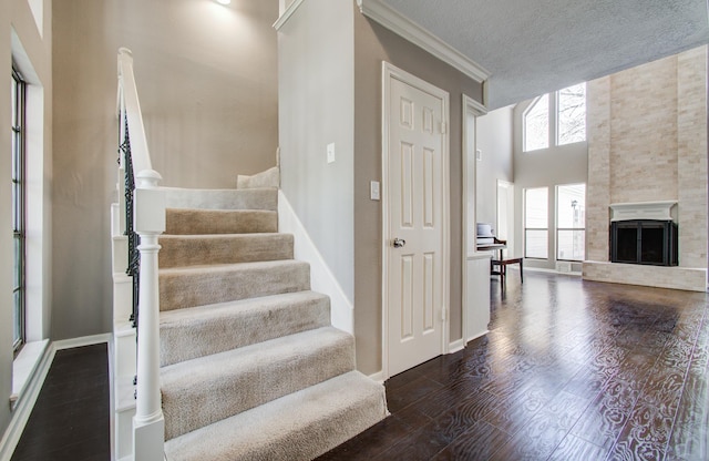1511 Calveryman Ln, Katy, TX 77449 - stairway featuring wood finished floors, crown molding, a fireplace with raised hearth, and a high ceiling