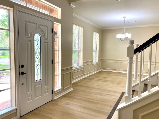 3210 Echo Mountain Dr, Houston, TX 77345 - foyer entrance featuring light wood finished floors, crown molding, a chandelier, healthy amount of natural light, and a wainscoted wall
