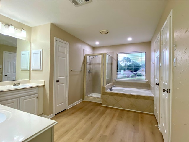 3210 Echo Mountain Dr, Houston, TX 77345 - bathroom with vanity, wood finished floors, a stall shower, a garden tub, and recessed lighting