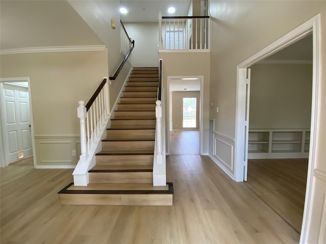3210 Echo Mountain Dr, Houston, TX 77345 - staircase with a decorative wall, wood finished floors, crown molding, a wainscoted wall, and a high ceiling