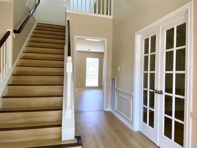 3210 Echo Mountain Dr, Houston, TX 77345 - stairway with wood finished floors, a wainscoted wall, french doors, and a decorative wall
