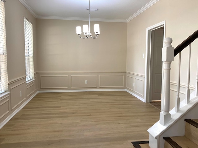 3210 Echo Mountain Dr, Houston, TX 77345 - unfurnished dining area featuring crown molding, stairway, a chandelier, light wood-type flooring, and a decorative wall