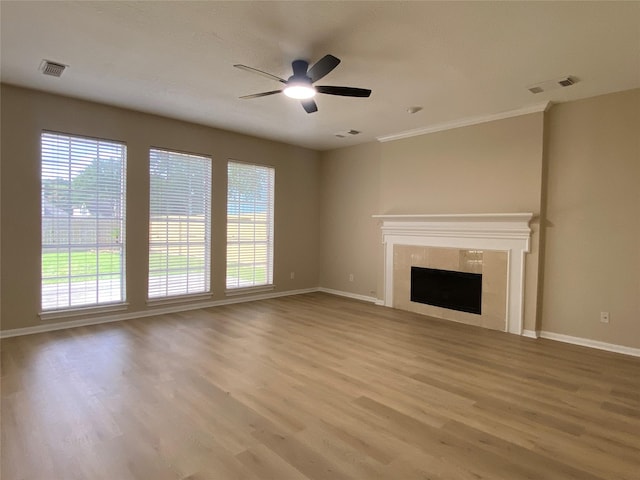 3210 Echo Mountain Dr, Houston, TX 77345 - unfurnished living room featuring healthy amount of natural light, wood finished floors, ceiling fan, a tile fireplace, and crown molding