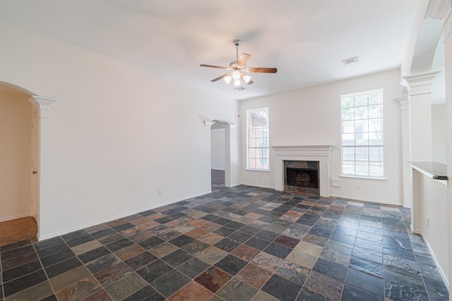 7314 Mountain Valley Dr, Houston, TX 77095 - unfurnished living room with ceiling fan, stone tile floors, a tile fireplace, arched walkways, and decorative columns