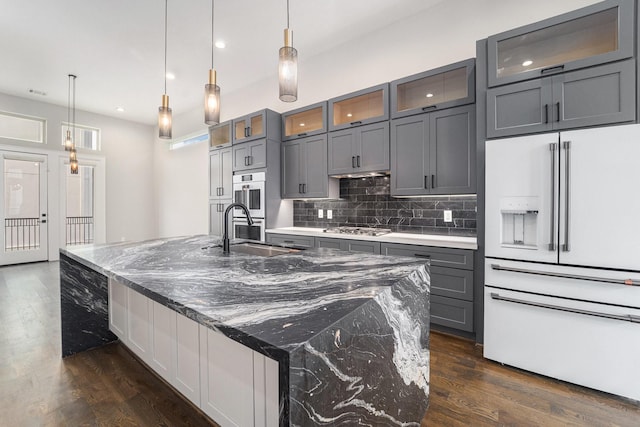 2221 Francis St, Houston, TX 77004 - kitchen featuring appliances with stainless steel finishes, gray cabinetry, dark wood-style flooring, decorative backsplash, and a spacious island