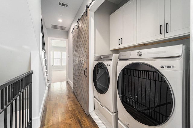 2221 Francis St, Houston, TX 77004 - washroom featuring a barn door, separate washer and dryer, wood finished floors, cabinet space, and recessed lighting