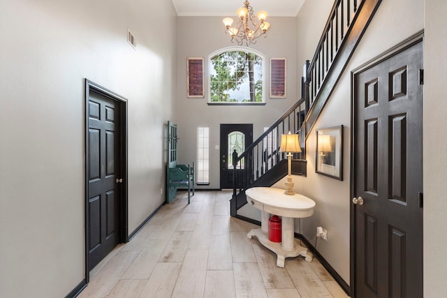 96 N Acacia Park Cir, The Woodlands, TX 77382 - foyer with stairs, a chandelier, a high ceiling, light wood finished floors, and crown molding