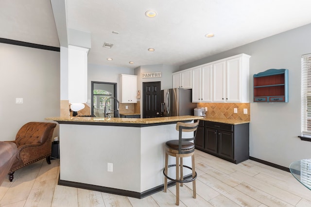 96 N Acacia Park Cir, The Woodlands, TX 77382 - kitchen with stainless steel fridge, light wood-style floors, decorative backsplash, light stone counters, and recessed lighting