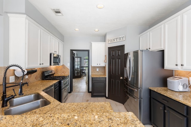 96 N Acacia Park Cir, The Woodlands, TX 77382 - kitchen with stainless steel appliances, white cabinetry, tasteful backsplash, light stone counters, and recessed lighting