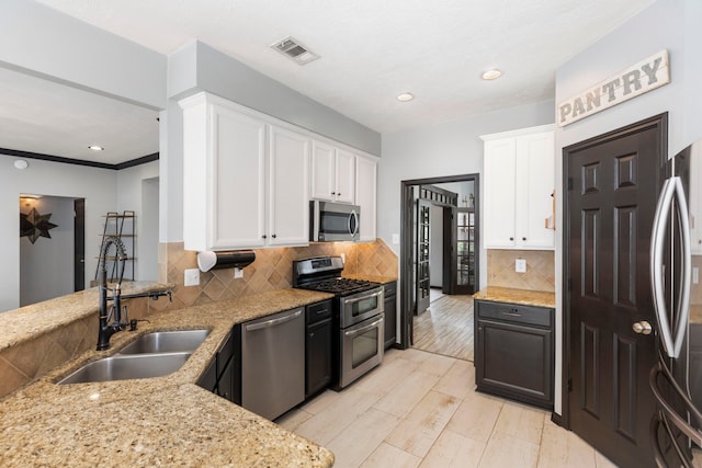 96 N Acacia Park Cir, The Woodlands, TX 77382 - kitchen with stainless steel appliances, light stone countertops, white cabinets, decorative backsplash, and light wood-style flooring