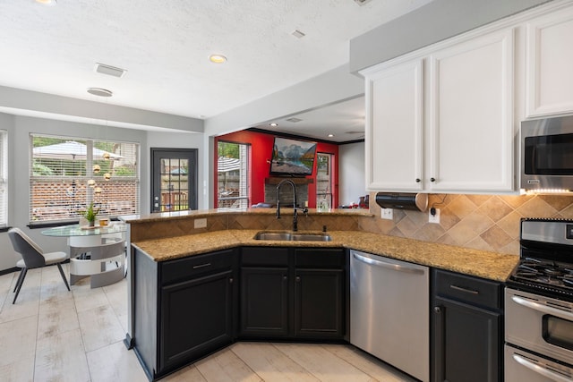 96 N Acacia Park Cir, The Woodlands, TX 77382 - kitchen with appliances with stainless steel finishes, white cabinetry, a peninsula, light stone countertops, and recessed lighting