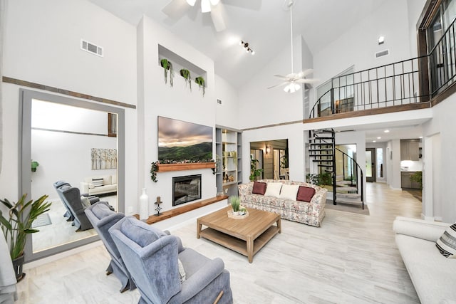 6803 Las Brisas Dr, Houston, TX 77083 - living room featuring ceiling fan, a glass covered fireplace, stairs, high vaulted ceiling, and marble look tiles