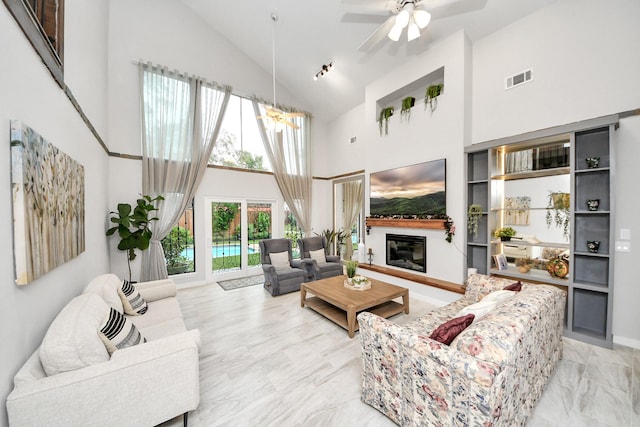 6803 Las Brisas Dr, Houston, TX 77083 - living area with high vaulted ceiling, a glass covered fireplace, light marble finish flooring, a chandelier, and a ceiling fan