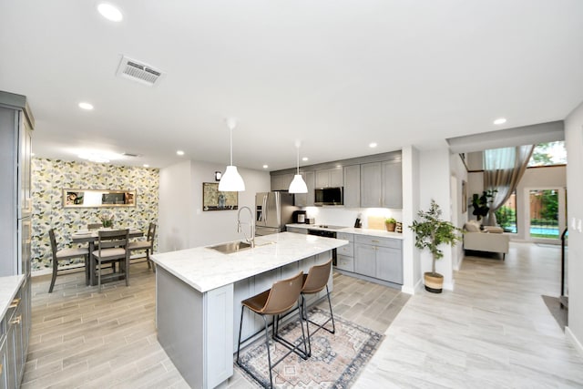 6803 Las Brisas Dr, Houston, TX 77083 - kitchen with gray cabinetry, stainless steel appliances, recessed lighting, a kitchen bar, and a center island with sink