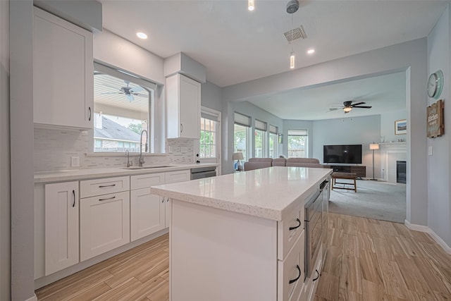 21002 Beech Landing Ln, Katy, TX 77450 - kitchen with ceiling fan, a kitchen island, open floor plan, backsplash, and light wood-type flooring
