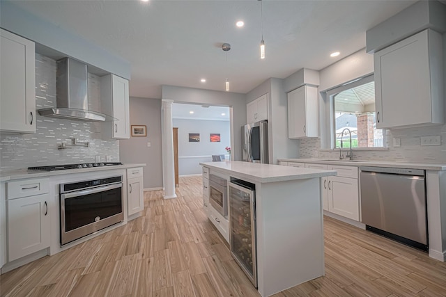 21002 Beech Landing Ln, Katy, TX 77450 - kitchen featuring appliances with stainless steel finishes, wall chimney range hood, wine cooler, light countertops, and decorative backsplash