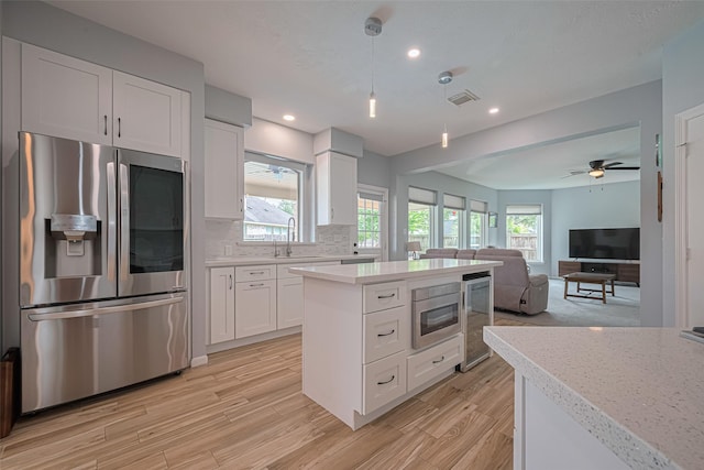 21002 Beech Landing Ln, Katy, TX 77450 - kitchen with stainless steel refrigerator with ice dispenser, light countertops, light wood-style flooring, white cabinets, and hanging light fixtures