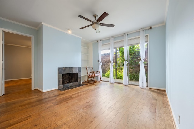 2829 Timmons Ln Unit 101, Houston, TX 77027 - unfurnished living room featuring wood finished floors, ornamental molding, a ceiling fan, and a tile fireplace