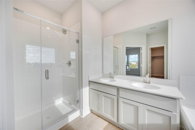 13208 Opera Dr, Houston, TX 77047 - full bath with a stall shower, double vanity, a walk in closet, and wood finished floors