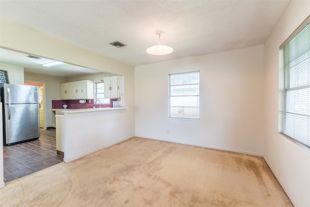 7734 El Rancho St, Houston, TX 77087 - kitchen featuring freestanding refrigerator, carpet floors, white cabinetry, a peninsula, and light countertops