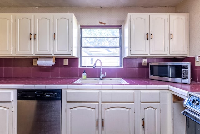 7734 El Rancho St, Houston, TX 77087 - kitchen with appliances with stainless steel finishes, white cabinets, and tile countertops