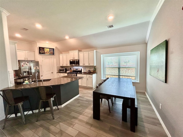 20130 New Sunrise Trl, Cypress, TX 77433 - kitchen with appliances with stainless steel finishes, a peninsula, ornamental molding, vaulted ceiling, and tasteful backsplash