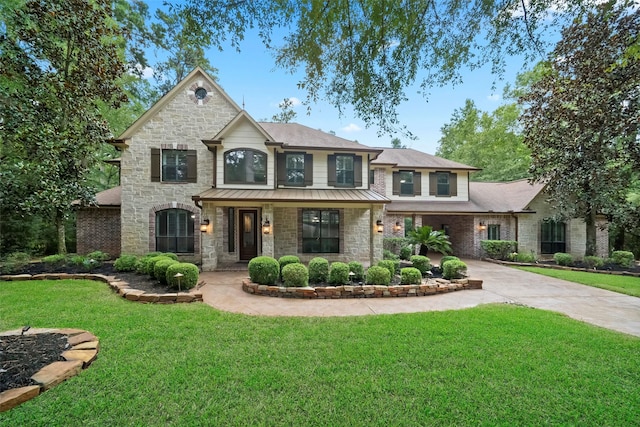 10332 Hunter Creek Ln, Conroe, TX 77304 - view of front facade featuring stone siding, a front yard, a standing seam roof, and driveway