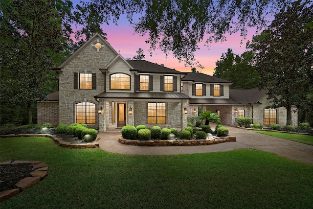 10332 Hunter Creek Ln, Conroe, TX 77304 - french country style house featuring stone siding, a standing seam roof, a lawn, and concrete driveway