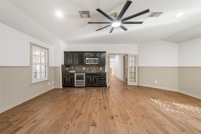 10332 Hunter Creek Ln, Conroe, TX 77304 - unfurnished living room featuring beverage cooler, a wainscoted wall, wood finished floors, a ceiling fan, and lofted ceiling