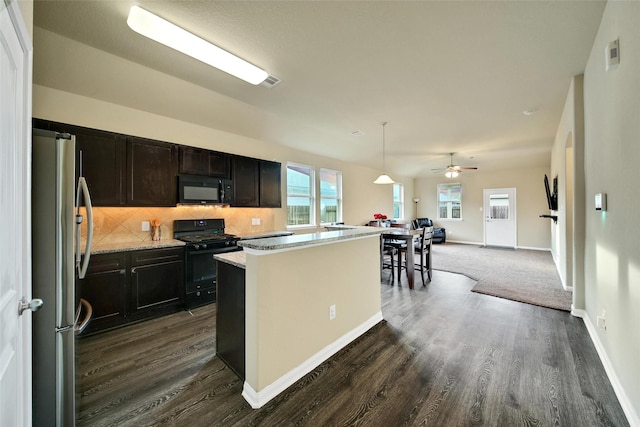 7427 Wheatley Gardens Dr, Houston, TX 77016 - kitchen featuring black appliances, dark wood finished floors, a center island, and tasteful backsplash