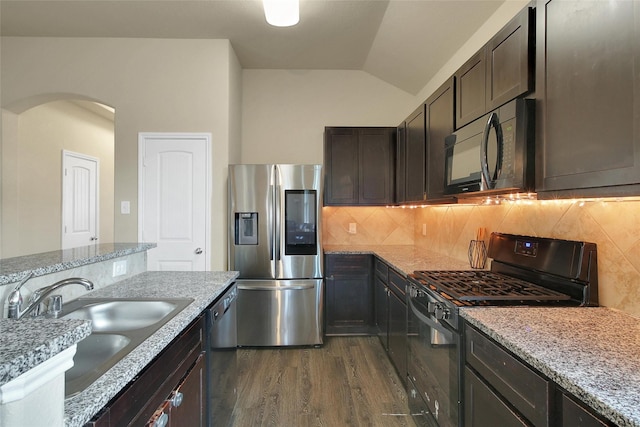 7427 Wheatley Gardens Dr, Houston, TX 77016 - kitchen with stainless steel refrigerator with ice dispenser, black gas stove, dark wood-style floors, arched walkways, and lofted ceiling