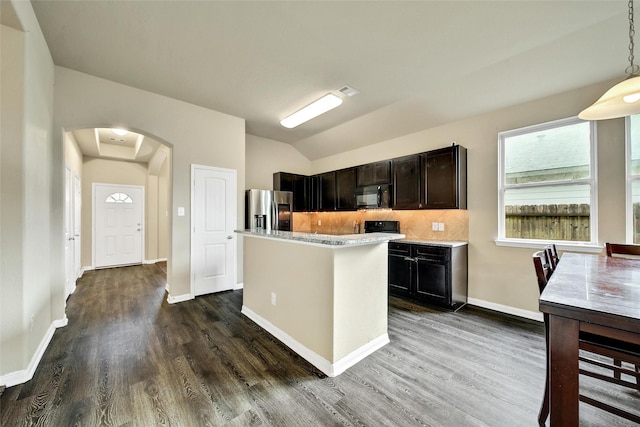 7427 Wheatley Gardens Dr, Houston, TX 77016 - kitchen with black microwave, stainless steel fridge with ice dispenser, arched walkways, tasteful backsplash, and dark wood-style flooring