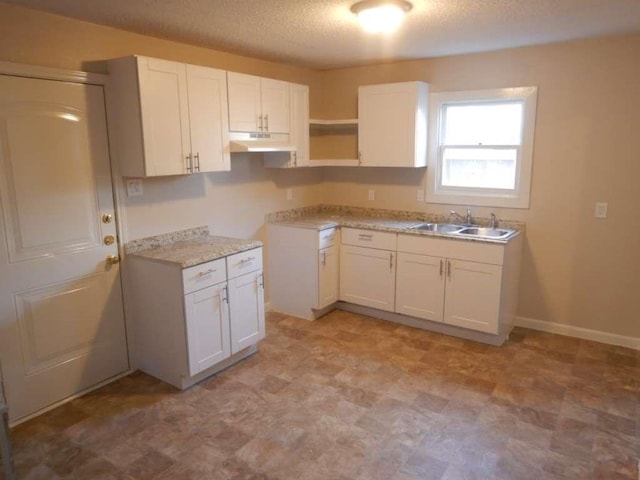 4218 Buck St, Houston, TX 77020 - kitchen featuring under cabinet range hood, white cabinetry, a textured ceiling, light countertops, and light floors