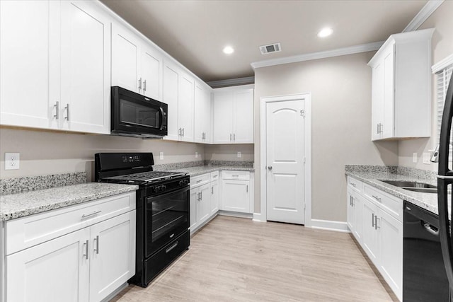 7970 Fowlie St, Houston, TX 77028 - kitchen with black appliances, ornamental molding, white cabinets, light wood-style flooring, and light stone counters