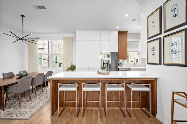 1801 Oneil St Unit C, Houston, TX 77019 - kitchen with appliances with stainless steel finishes, white cabinets, light countertops, a chandelier, and a kitchen breakfast bar