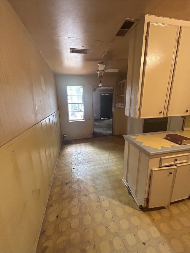 1904 Lillian St, Pasadena, TX 77502 - kitchen with light flooring, light countertops, ceiling fan, wainscoting, and white cabinets