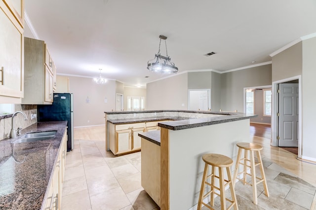 131 Canary Ln, Coldspring, TX 77331 - kitchen with crown molding, a breakfast bar area, a spacious island, freestanding refrigerator, and decorative light fixtures