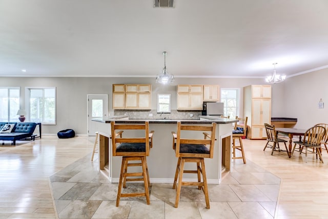 131 Canary Ln, Coldspring, TX 77331 - kitchen with light brown cabinetry, ornamental molding, dark countertops, a chandelier, and a kitchen bar