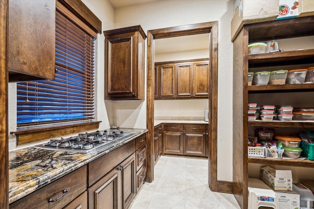 3751 Aberdeen Way, Houston, TX 77025 - kitchen featuring stainless steel gas stovetop, light stone countertops, light tile patterned flooring, and dark brown cabinetry