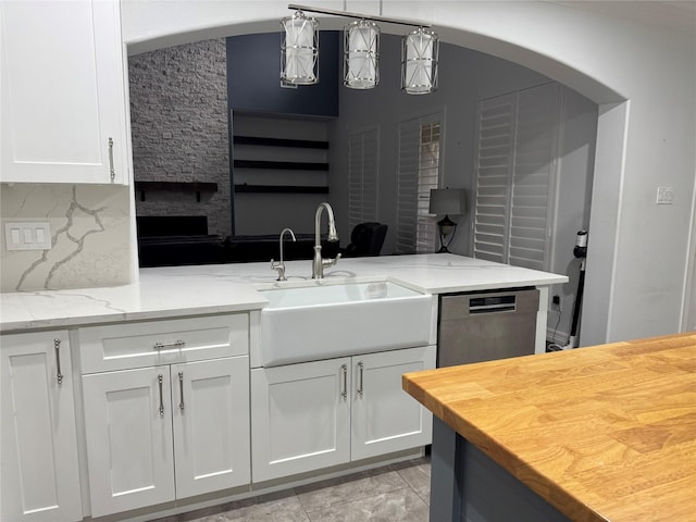 14410 Brentshire Ln, Houston, TX 77069 - kitchen featuring arched walkways, stainless steel dishwasher, white cabinetry, light stone counters, and tasteful backsplash