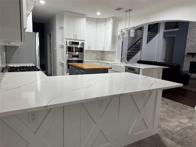 14410 Brentshire Ln, Houston, TX 77069 - kitchen featuring a peninsula, stainless steel appliances, white cabinets, wooden counters, and recessed lighting