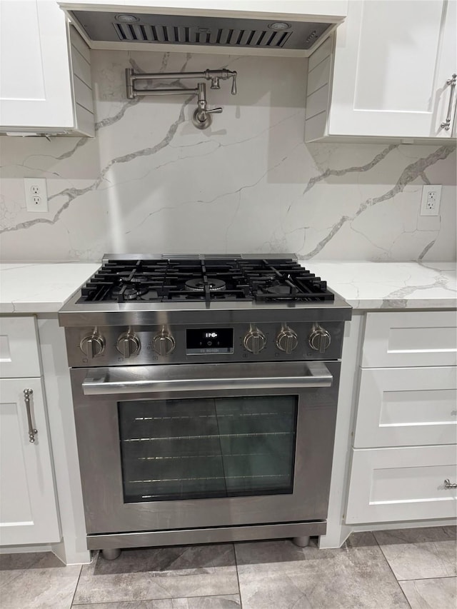 14410 Brentshire Ln, Houston, TX 77069 - kitchen with high end stainless steel range, white cabinetry, light stone counters, exhaust hood, and backsplash