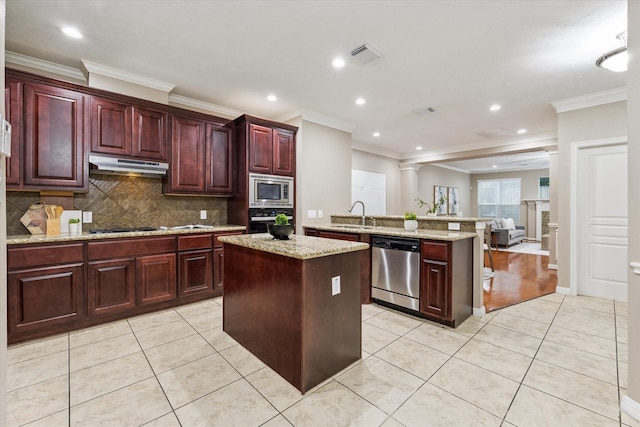 1339 Ella Pl, Houston, TX 77008 - kitchen with appliances with stainless steel finishes, under cabinet range hood, dark brown cabinets, a center island, and a peninsula
