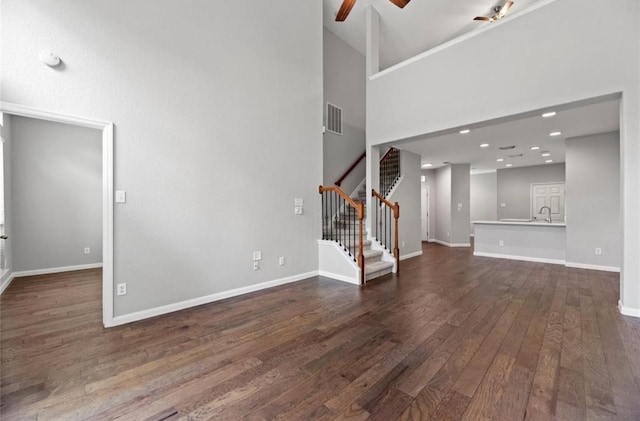 8814 Silent Willow Ln, Sugar Land, TX 77479 - unfurnished living room with stairway, dark wood finished floors, a ceiling fan, and a high ceiling