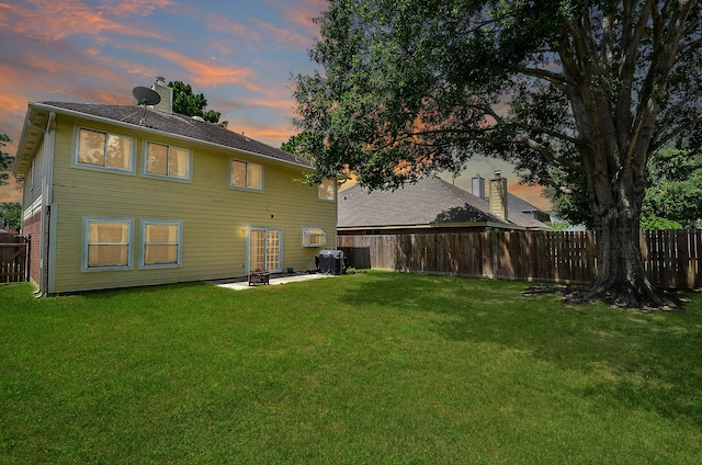 15018 Moss Boulder Ct, Houston, TX 77084 - back of house at dusk featuring a fenced backyard, a chimney, and a patio