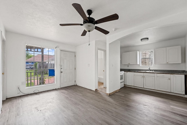 1922 Des Jardines St, Houston, TX 77023 - unfurnished living room featuring wood finished floors, a ceiling fan, a textured ceiling, and arched walkways