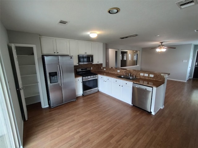 2518 Skyview Cove Ct, Houston, TX 77047 - kitchen with stainless steel appliances, a peninsula, wood finished floors, white cabinetry, and tasteful backsplash