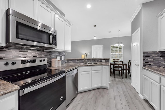 3534 Cork Dr, Houston, TX 77047 - kitchen with appliances with stainless steel finishes, decorative backsplash, white cabinets, a peninsula, and decorative light fixtures